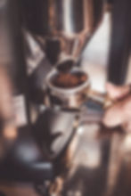 An espresso grinder grinding fine coffee grinds into a portafilter.